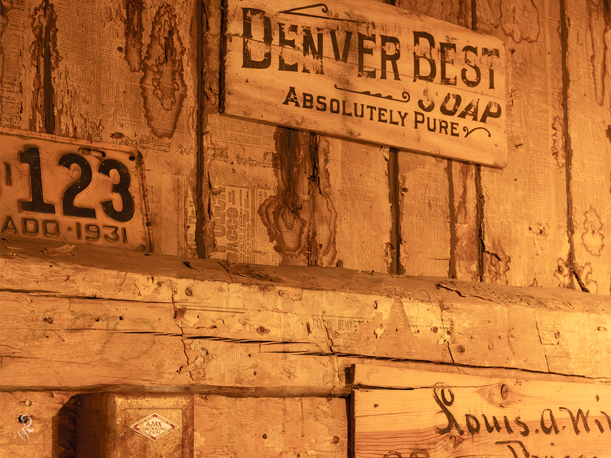 A photo from the Frisco, Colorado General Store of an Antique wall with rich textures and signs. One says, "Denver Best Soap: Absolutely Pure."